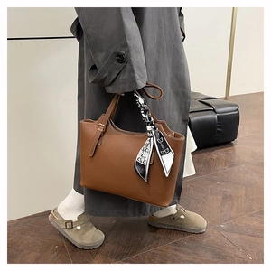Detail of caramel leather tote bag with silk scarf decoration and side buckle accent