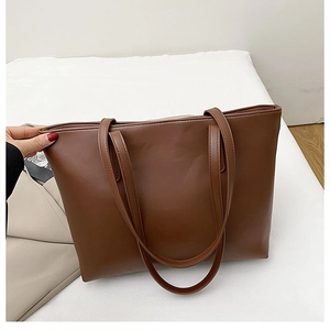 Detail view of smooth dark brown leather texture and stitching on large tote bag