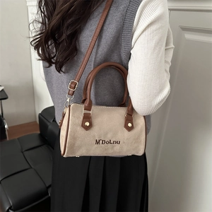 Sac Boston en daim beige avec bandoulière en cuir marron porté par un mannequin