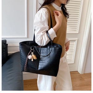 Close-up of black crocodile texture tote bag with sports themed baseball bag charm