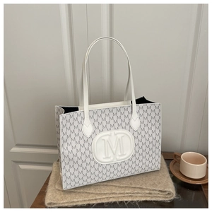 Close-up of white tote bag with M-letter jacquard and embossed leather logo detail