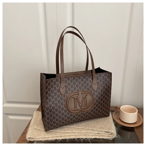 Macro shot of brown faux leather tote bag with M-pattern print and embossed logo
