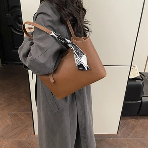 Caramel brown leather tote bag with silk scarf detail worn by model in grey coat