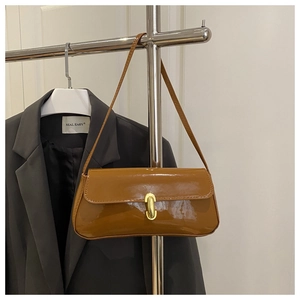 Détail du sac bandoulière en cuir verni caramel avec boucle dorée rotative ovale