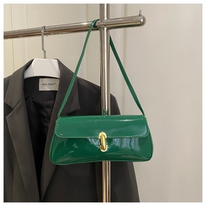 Gros plan d'un sac porté épaule en cuir verni vert avec fermoir doré sur support
