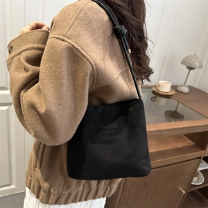 Schicke schwarze Wildleder-Beuteltasche mit geknotetem Riemen zum braunen Wollmantel
