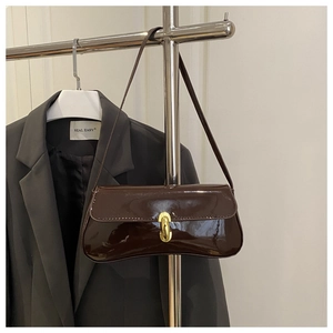 Détail du sac baguette en cuir verni marron foncé avec boucle métallique dorée élégante