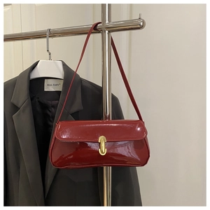 Détail du sac en cuir verni rouge foncé avec fermoir capsule doré sur la bandoulière