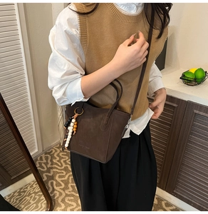 Detail of dark brown matte tote bag with beaded tassel and shoulder strap on a model