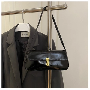 Détail du sac sous le bras noir brillant avec boucle en métal doré et texture vernie