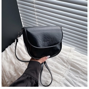 Détail d'un sac selle en cuir verni noir brillant avec logo HYLIZZA embossé