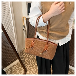 Close-up of leopard print suede tote with brown leather knotted handles and gold accents