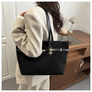 Grand sac cabas noir en daim avec boucle dorée porté à l'épaule pour un style élégant