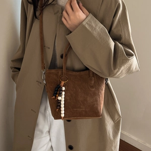 Brown suede bucket bag with stylish wooden bead tassel for autumn and winter outfits