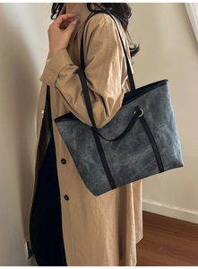 Lifestyle shot of large gray contrast tote bag with black leather straps and gold buckles