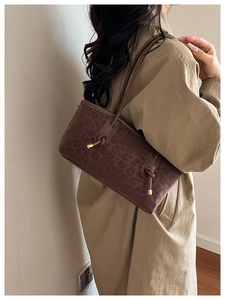 Detail of leopard print tote bag with leather strap knot and gold metal accents
