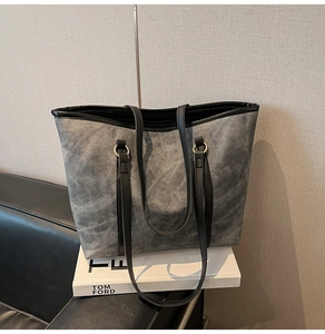 Detail of grey washed texture tote bag with black leather straps and metal rings