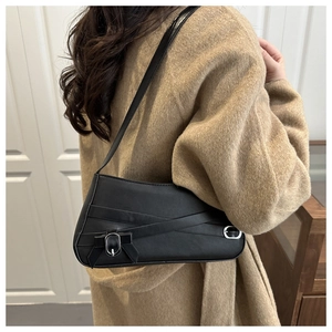 Detail of black leather baguette bag with silver buckle and bow knot strap detail