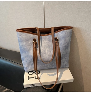 Detail of blue and white textured canvas tote bag with brown leather handles and rings