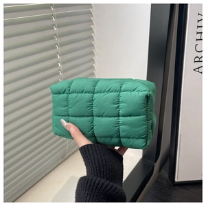 Nahaufnahme der grünen gesteppten Clutch mit weicher Textur und Reißverschluss-Detail