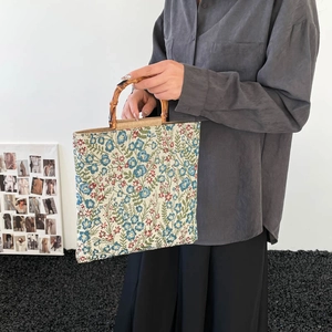Floral jacquard tote bag with natural bamboo handles shown in a modern studio setting