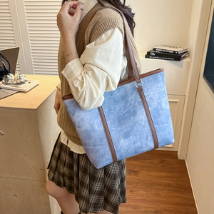 Blue denim texture tote bag with brown leather handles for stylish daily commuting wear