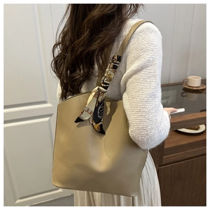 Detail of khaki leather tote bag with decorative printed scarf on shoulder strap