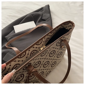 Detail of printed canvas tote bag with brown leather handles and secure zipper closure