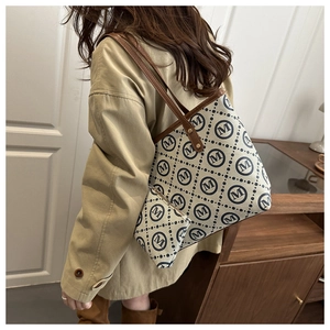 Detail of canvas tote bag with repeat M logo and matching pouch on model