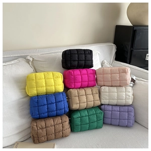 Détail de trousses de maquillage matelassées colorées sur un canapé blanc dans un décor