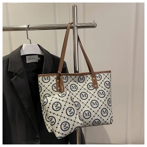 Macro view of patterned tote bag with M-print texture and brown leather strap detail