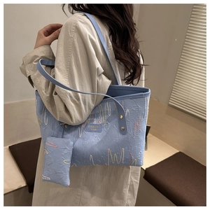 Close-up of light blue textured tote bag with wave embroidery and mini pouch