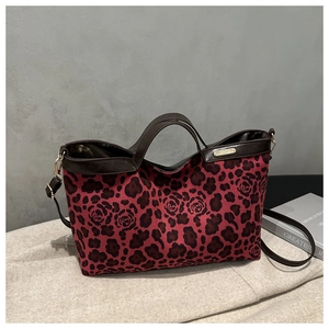 Detail of red leopard and floral print tote bag with brown leather handles and hardware