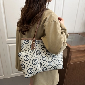 Women's cream and navy monogram tote bag set with brown straps shown on a model
