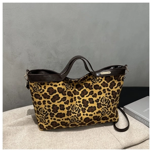 Close-up of leopard and rose print suede tote bag with brown leather handles and gold logo tag