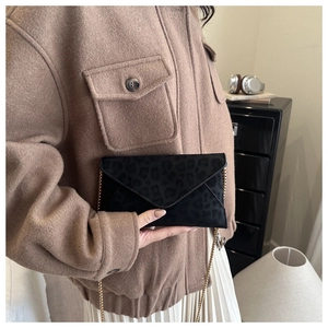 Detail of leopard print chain bag with gold strap styled on a textured autumn outfit