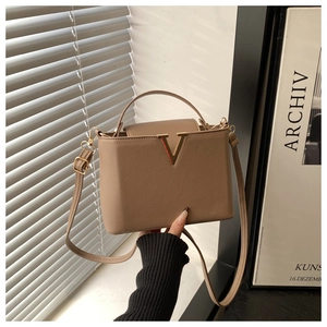 Détail d'un sac à main en cuir grainé kaki avec une grande boucle en métal doré en V