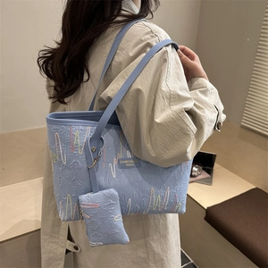 Blue embroidered tote bag with embossed texture and small coin purse attachment
