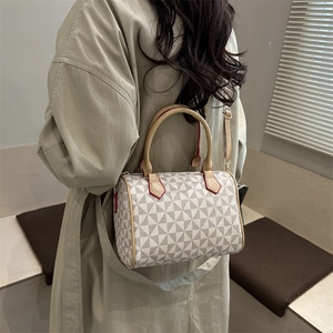 Modern Boston handbag with geometric patterns and brown leather straps worn on a trench coat