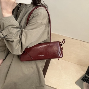 Borsa sottobraccio in pelle lucida bordeaux con nodo indossata con un trench beige