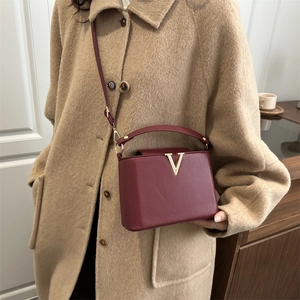 Sac à main chic en cuir bordeaux avec boucle en V dorée et bandoulière élégante
