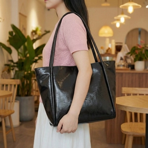 Close-up of a large black patent leather tote bag styled for elegant female commuting