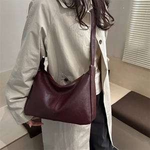 Retro burgundy half-moon shoulder bag with minimalist stitching shown on a model