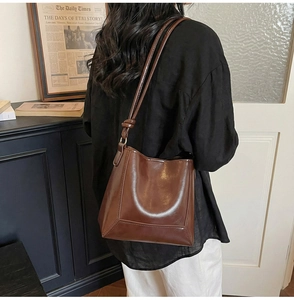 Brown leather tote bag with knotted shoulder straps shown on model in a retro setting