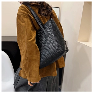 Close-up of the woven texture and spacious structure on this black leather tote bag