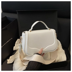 Detail of white leather handbag with scalloped flap, gold hardware and woven strap