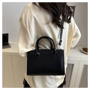 Detail of the black pleated leather tote bag showing vertical texture and silver hardware