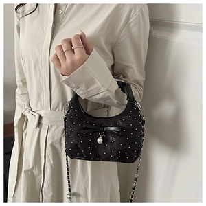 Close-up of black satin pleated crossbody bag with diamond bow and pearl pendant detail