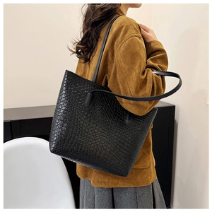 Model wearing a large black woven tote bag with a minimalist retro commuting style