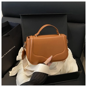 Detail of brown saddle handbag with white wide strap and golden hardware in gift box
